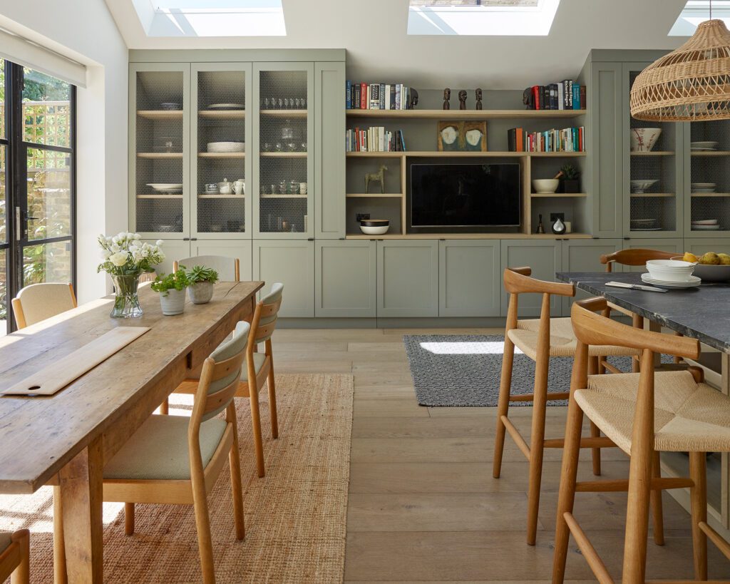 A dining room with a table and chairs, a television and cabinets.