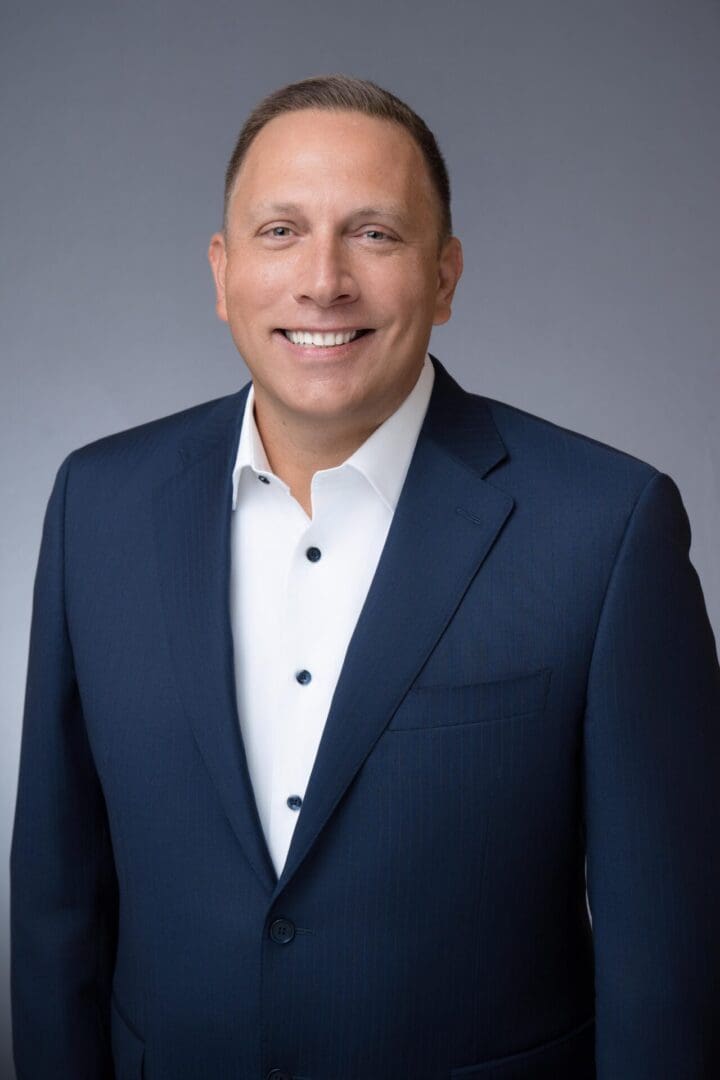 A man in a suit and tie smiling for the camera.